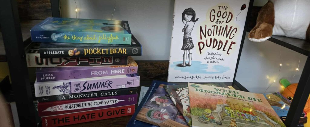 photo of books on my book shelf. a stack of 8 on the left and side. about 5 fanned out on the bottom. The Good for Nothing Puddle standing up in the back.